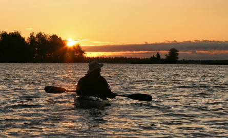 man in a kayak on a lake at sunrise